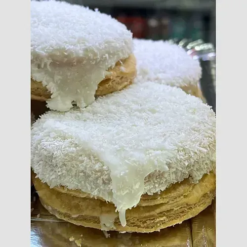 Un primer plano de una pila de panqueques con glaseado blanco y coco encima.