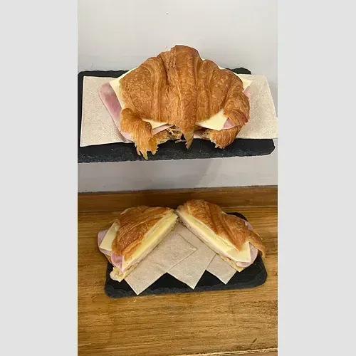 Dos croissants con jamón y queso están sentados sobre una mesa de madera.