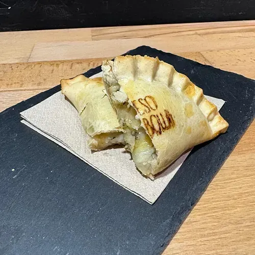 Un pastel al que se le ha quitado un mordisco está sobre una servilleta en una tabla de cortar.
