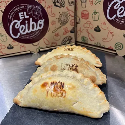 Un montón de empanadas están sobre una mesa con cajas al fondo.