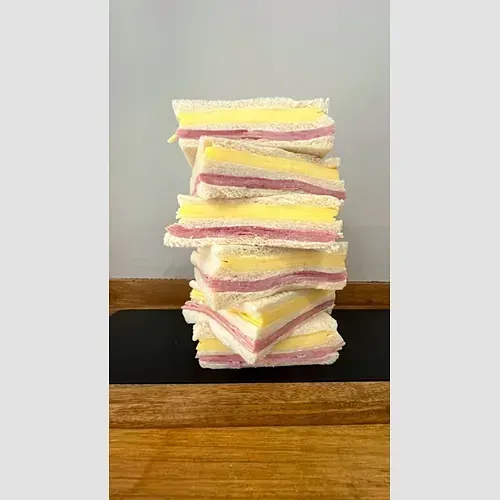 Una pila de sándwiches colocados uno encima del otro sobre una mesa de madera.