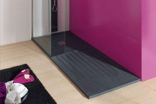 Un baño con una pared rosa y un plato de ducha negro.