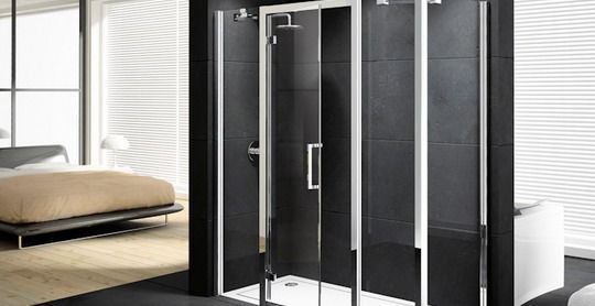 Un baño con cabina de ducha y una cama al fondo.