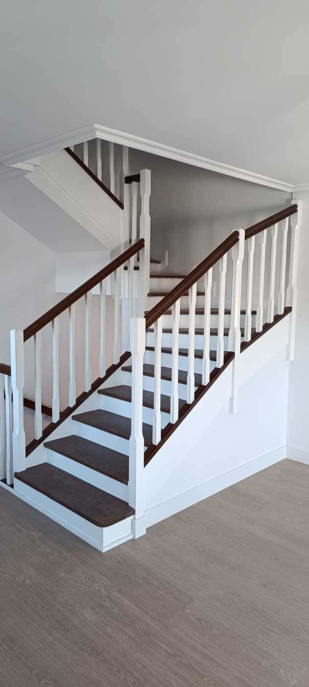 Escalera blanca con pasamanos marrones y escalones grises.