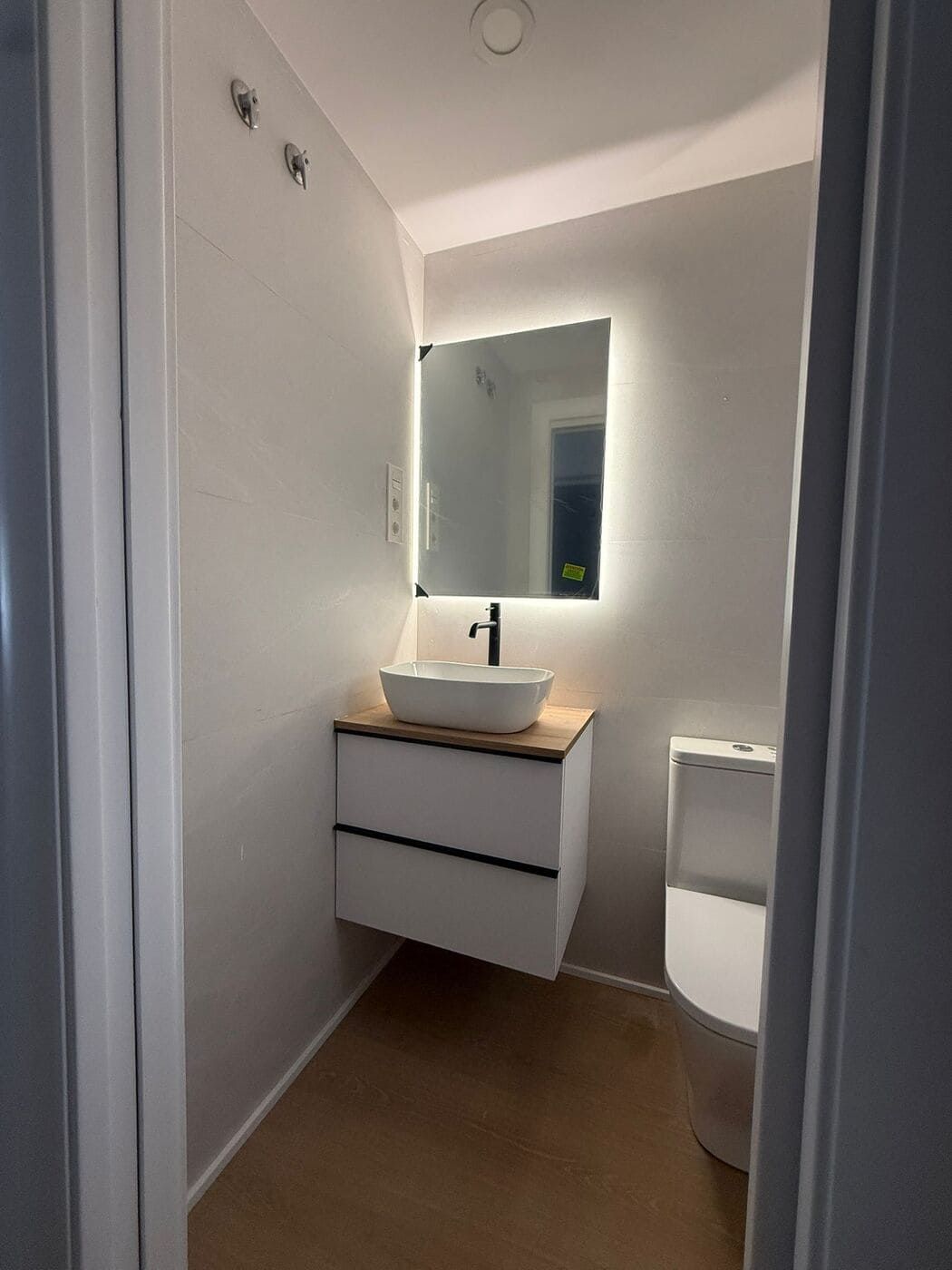 Cabina de ducha con puertas de cristal y WC en un baño con paredes alicatadas.