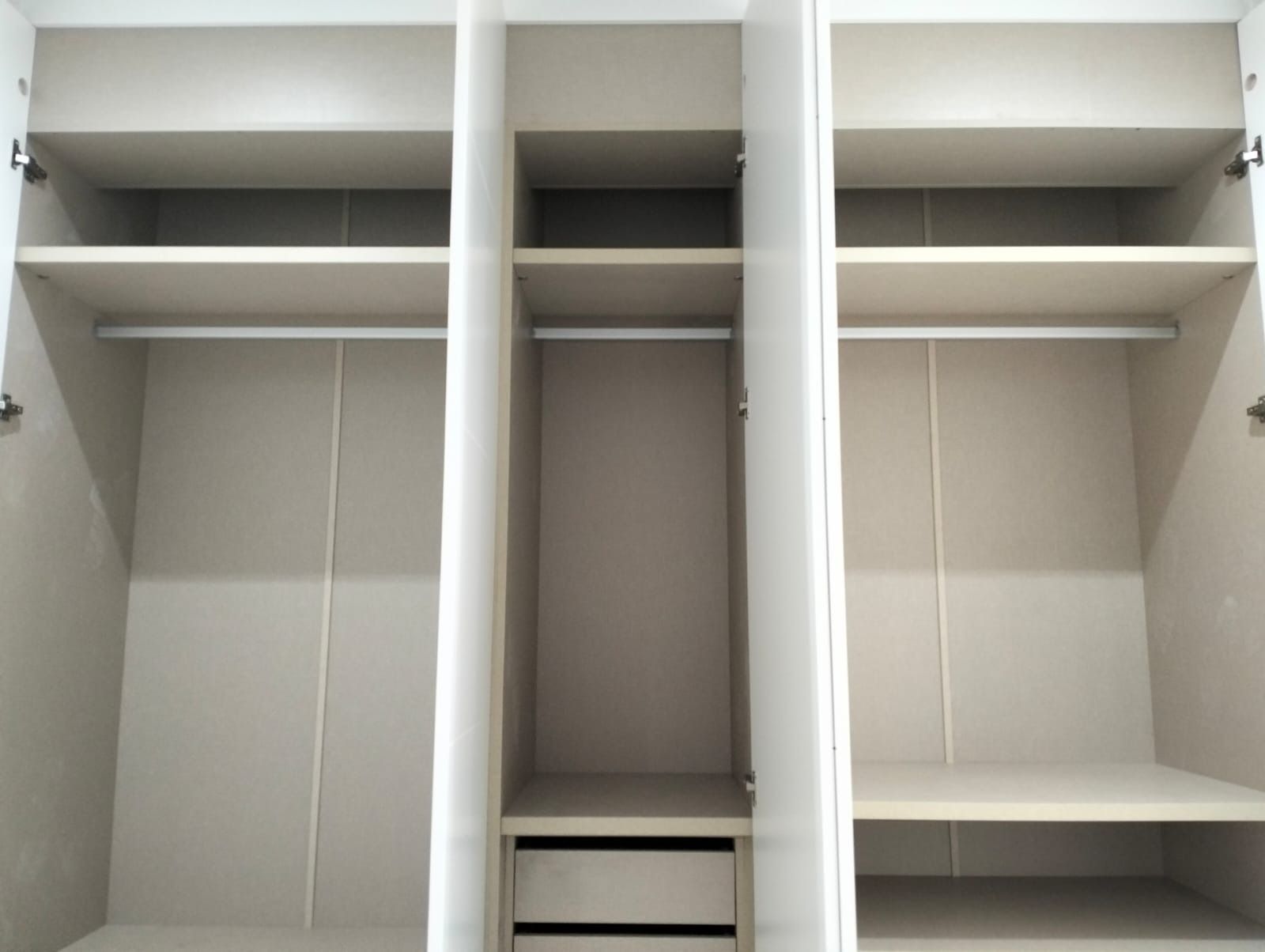 Armario blanco vacío con estantes, barras para colgar y un cajón.