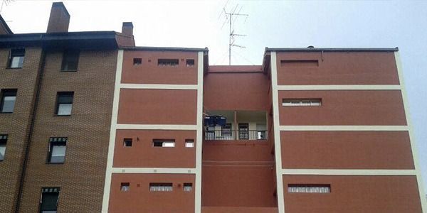 Edificio de apartamentos de ladrillo rojo con molduras blancas y antena en el techo.