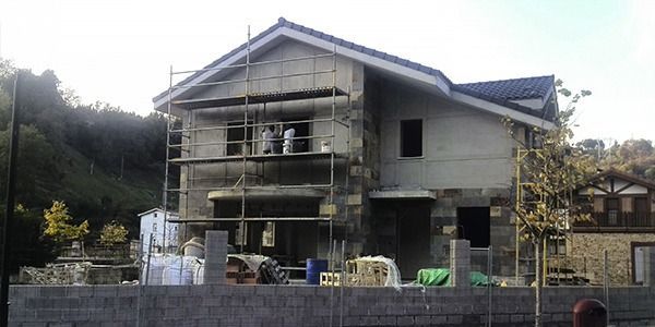Casa en construcción con andamios, paredes grises y techo oscuro.