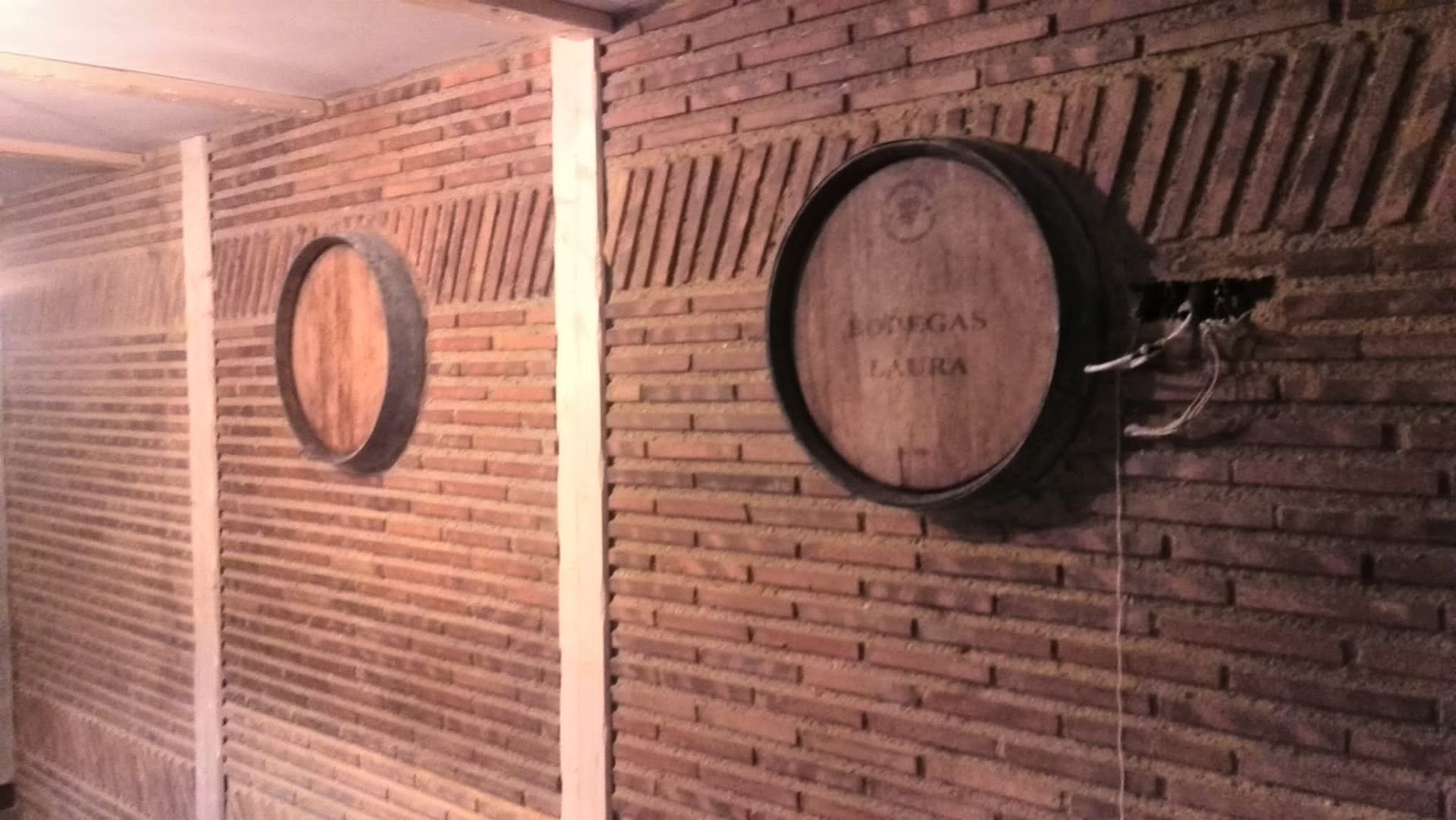 Pared de ladrillos con dos mitades de barril de madera montadas sobre ella.