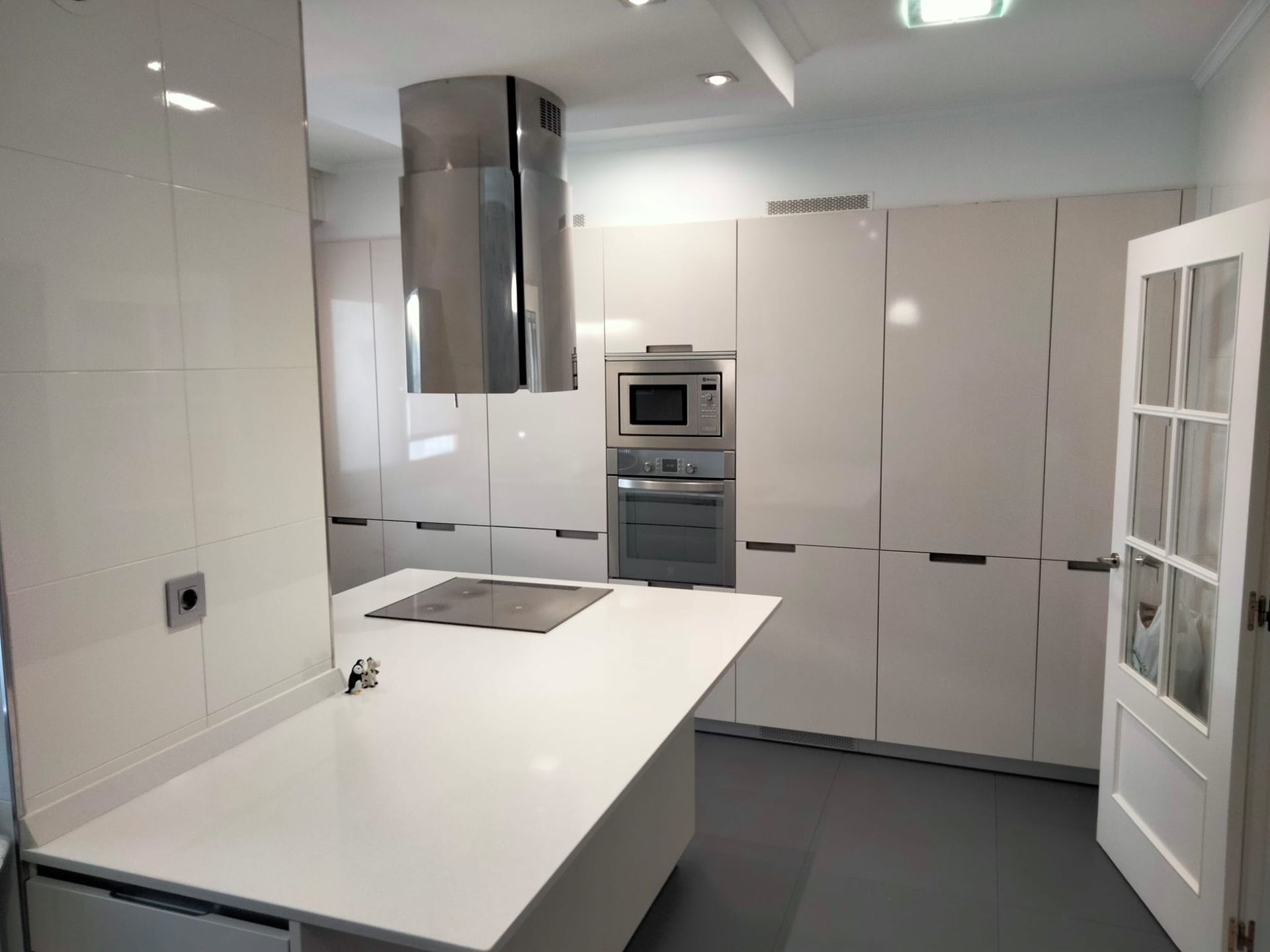 Cocina blanca moderna con electrodomésticos de acero inoxidable, gabinetes blancos e isla.