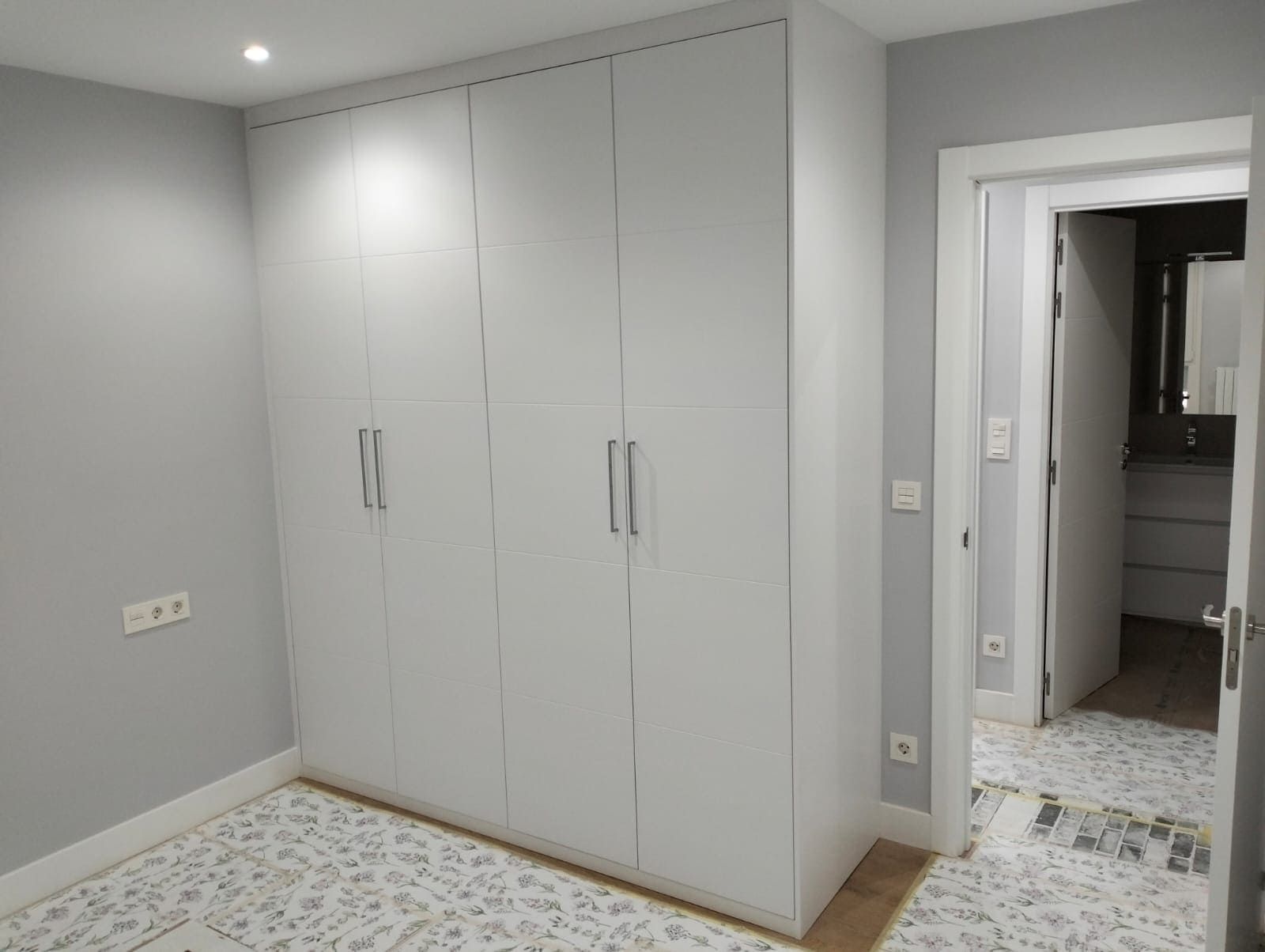 Dormitorio con un gran armario blanco y una puerta que da acceso a un baño.