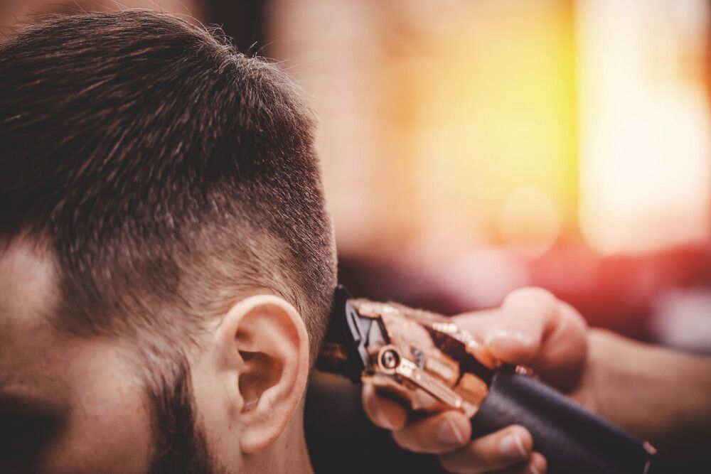 Un hombre se está cortando el pelo con una máquina barbera.
