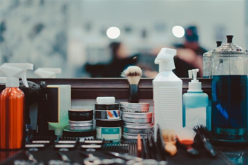 Una mesa con muchas botellas y cepillos encima en una barbería.