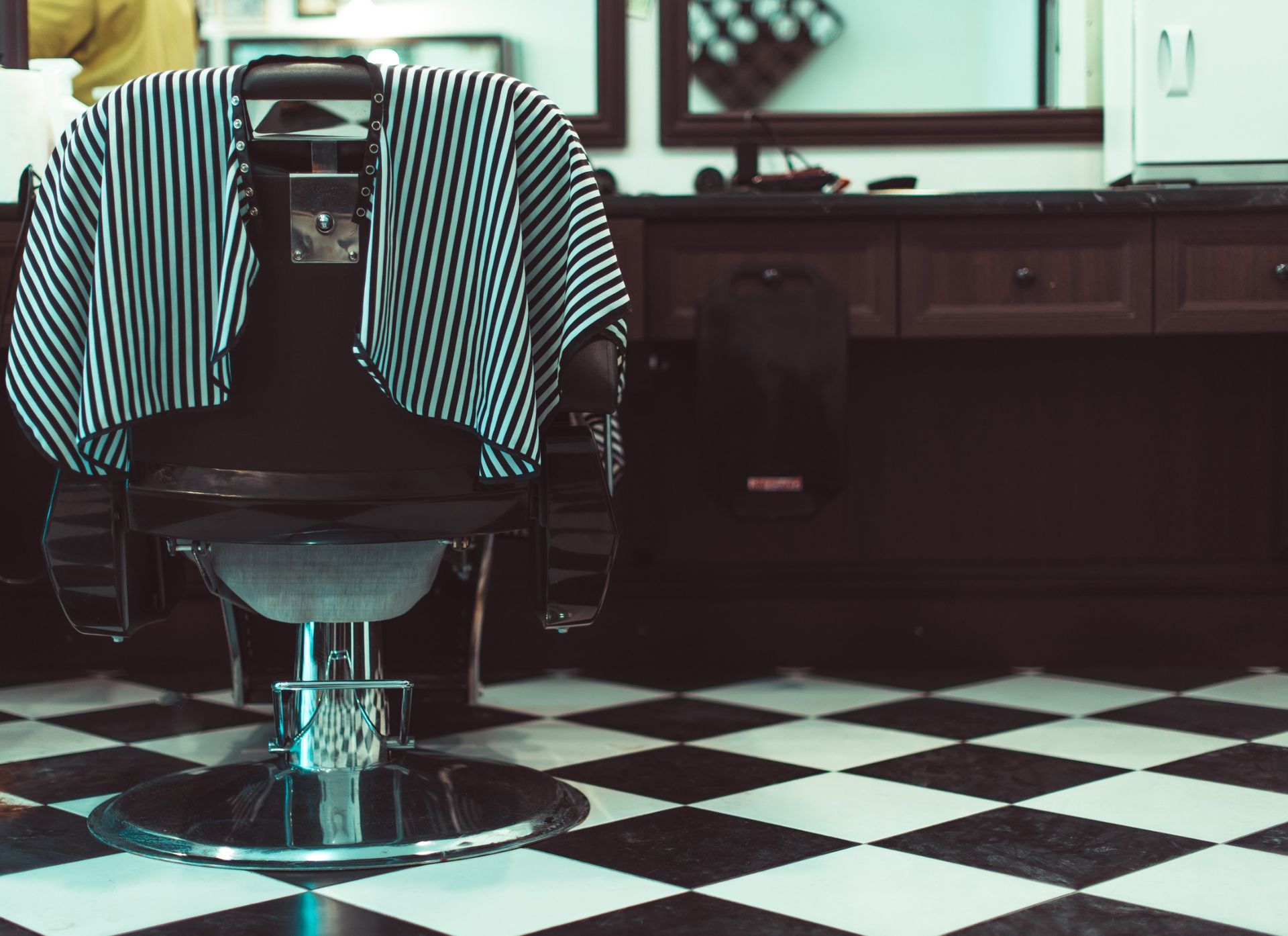Una silla de barbero en una barbería con suelo a cuadros.
