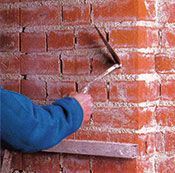 Un hombre está trabajando en una pared de ladrillos con una paleta.