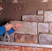 Una persona está colocando ladrillos en una pared de ladrillos.