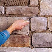 Una persona está aplicando mortero a una pared de piedra.