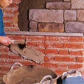 Un hombre está trabajando en una pared de ladrillos con una pala.