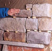 Una persona está colocando ladrillos en una pared.