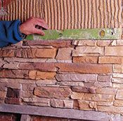 Una persona está usando un nivel para comprobar el nivel de una pared de piedra.