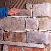 Una persona está colocando ladrillos en una pared.