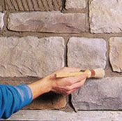 Una persona está pintando una pared de piedra con un pincel.