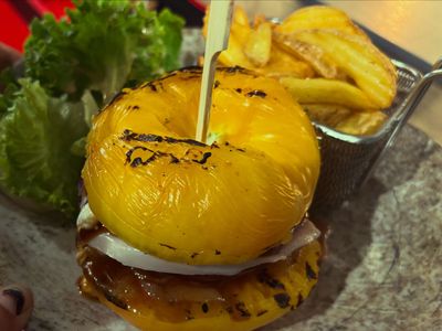 Hamburger grillé et frites dans un gobelet en métal servi sur une table.