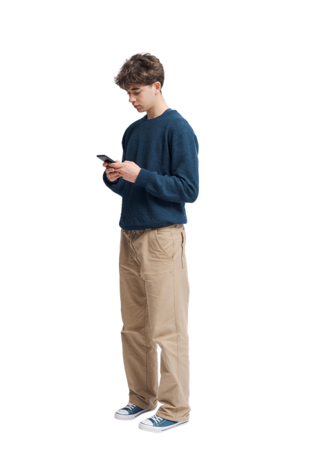 Une personne en pull et pantalon regarde un téléphone.