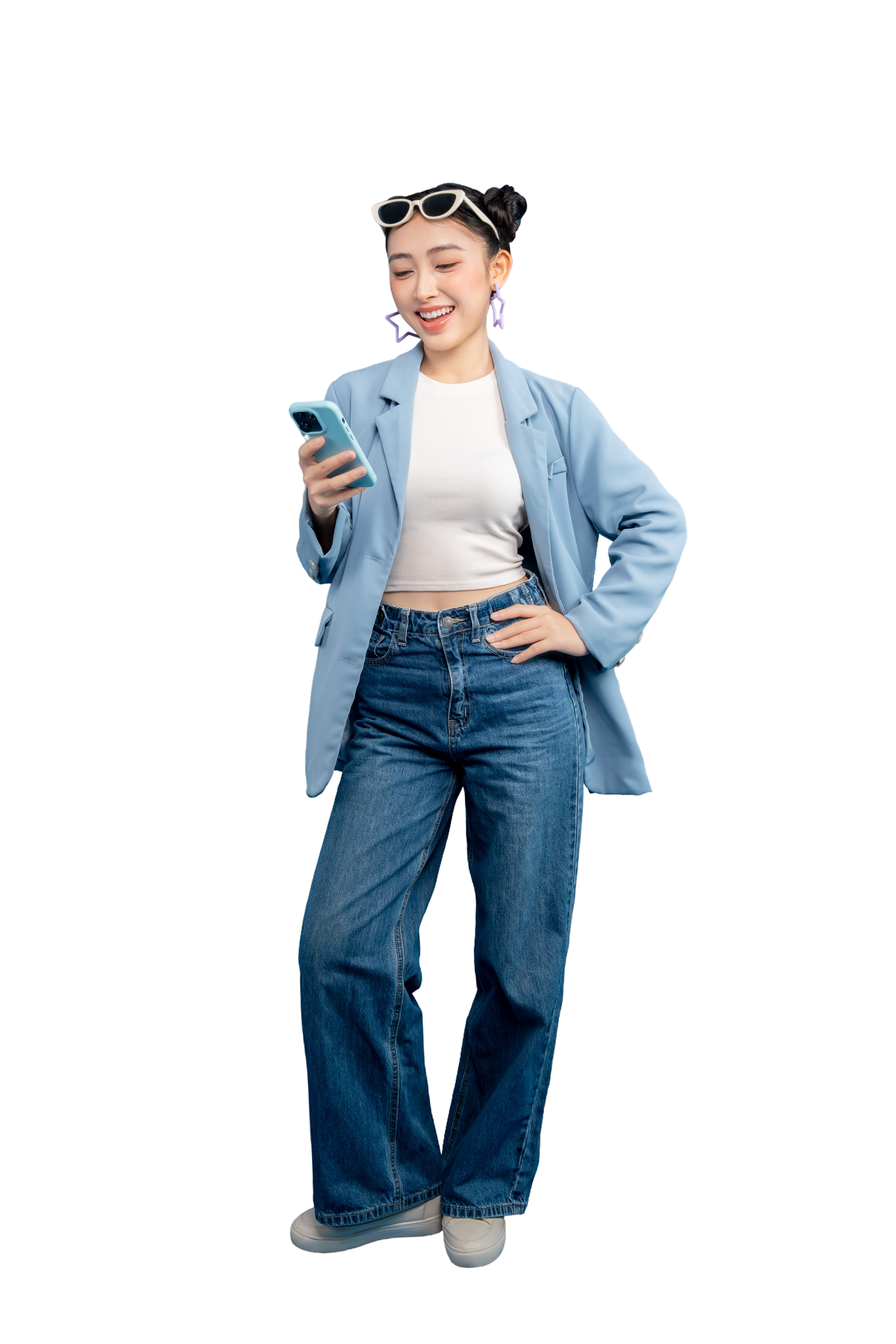 Personne vêtue d'un blazer et d'un jean, souriant en regardant son téléphone.
