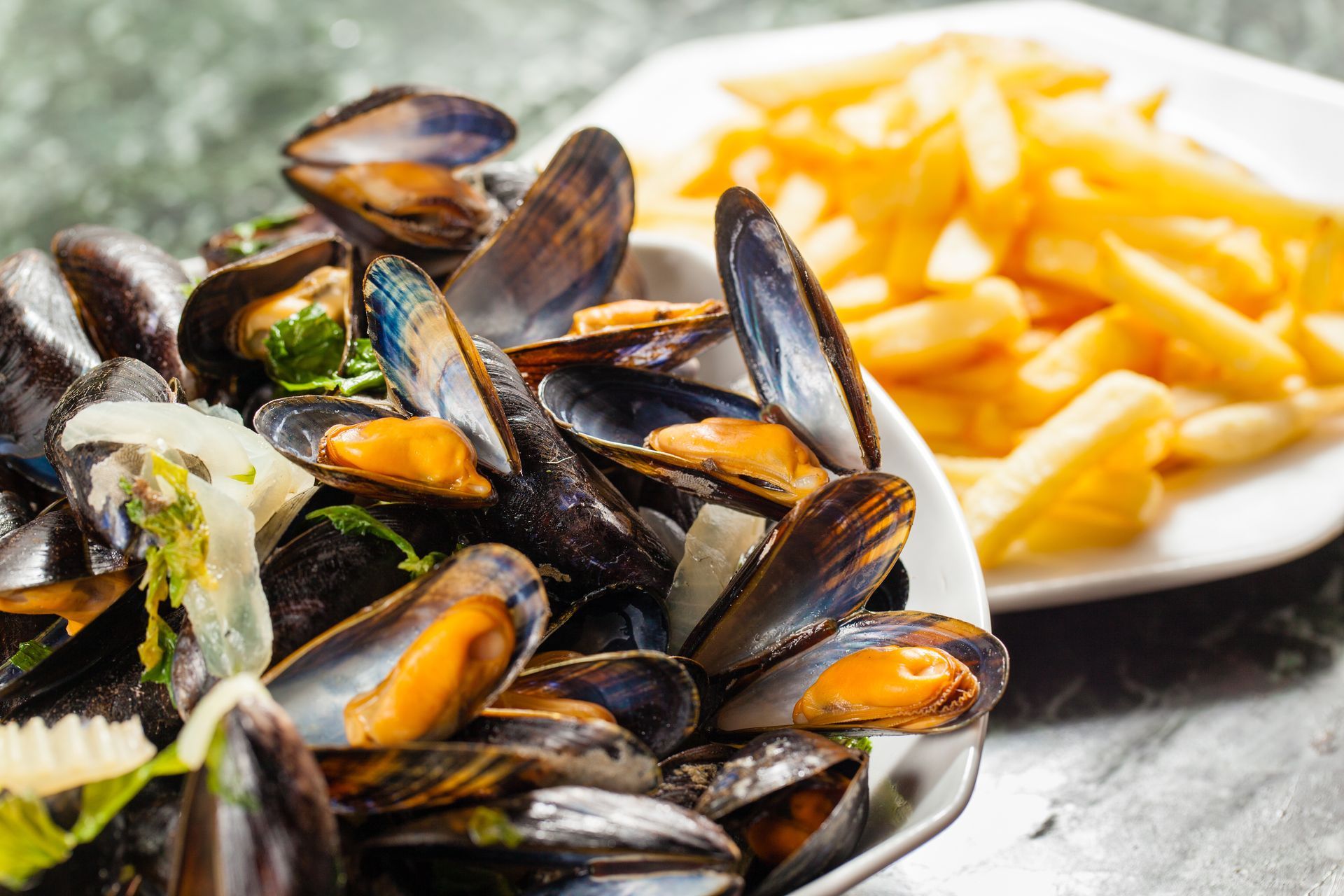 Moules à la sauce tomate avec des frites sur une assiette, servies sur une table.