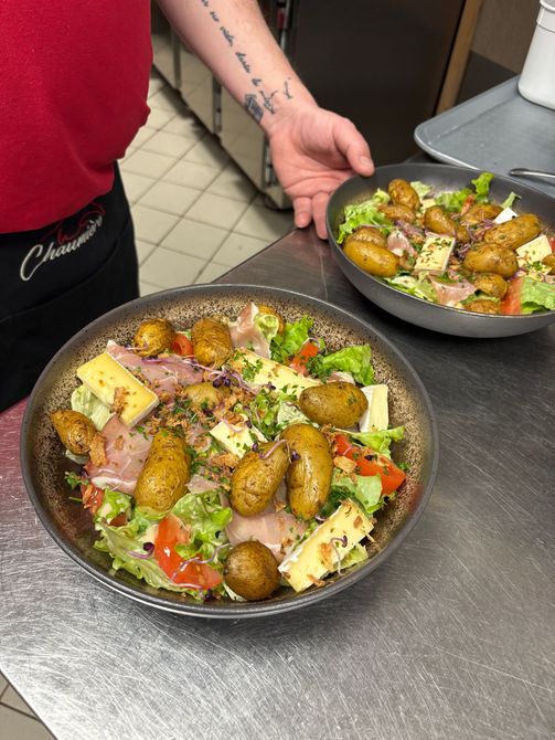Deux saladiers avec du poulet grillé, des pommes de terre, des tomates et du fromage sur un comptoir de cuisine.