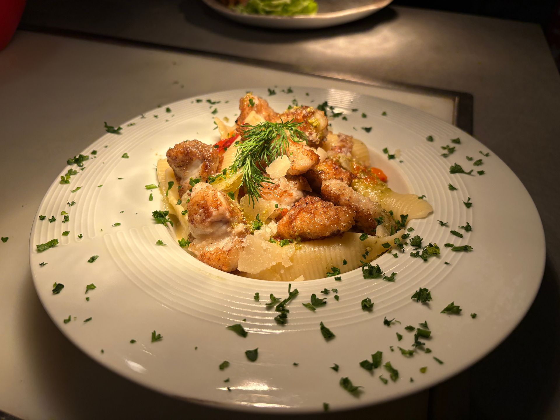 Pâtes aux crevettes garnies d'herbes aromatiques, servies dans une assiette.