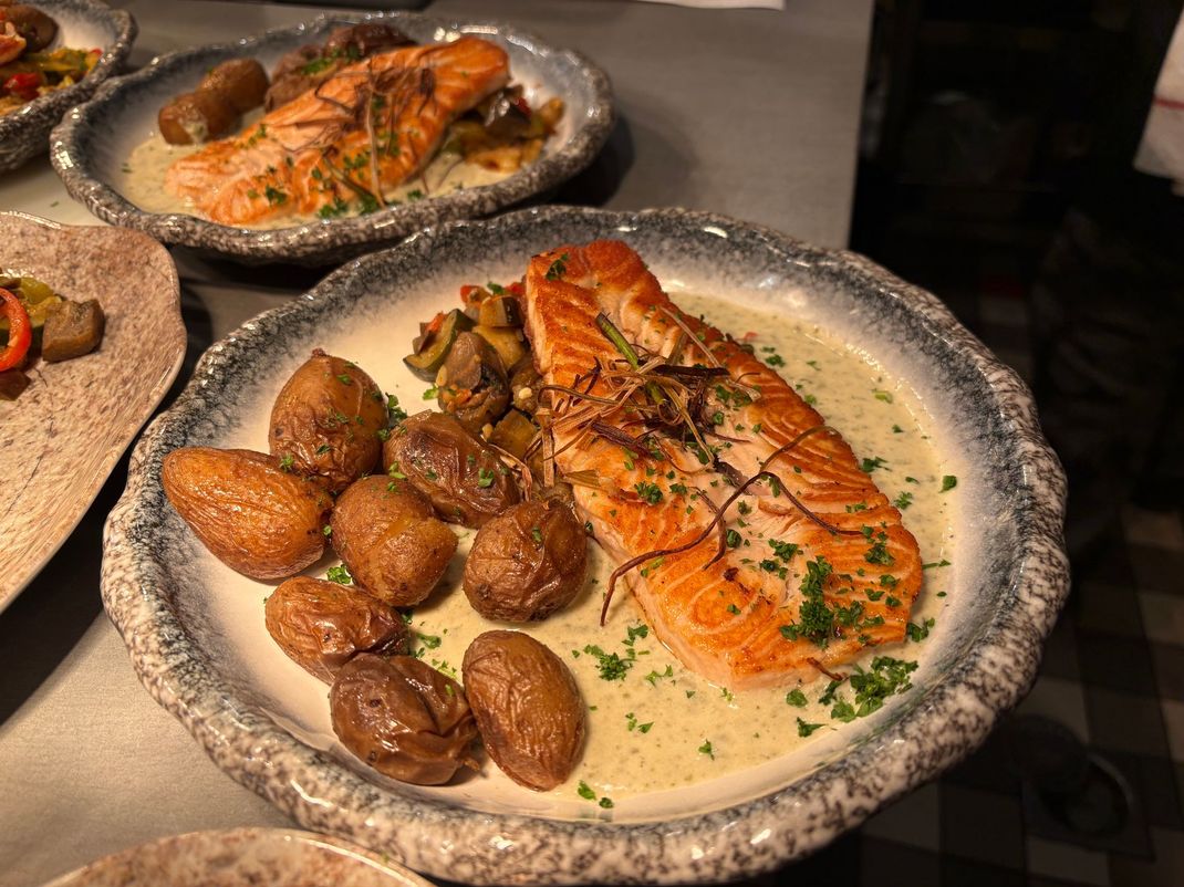 Saumon servi avec des pommes de terre à la sauce crémeuse, sur une table rustique.