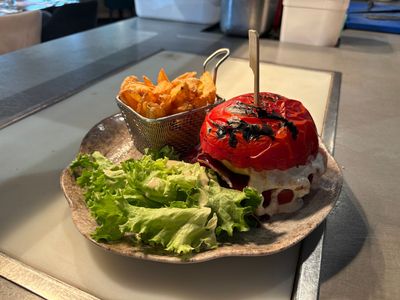 Burger gastronomique avec salade et frites dans une assiette, servi au restaurant.