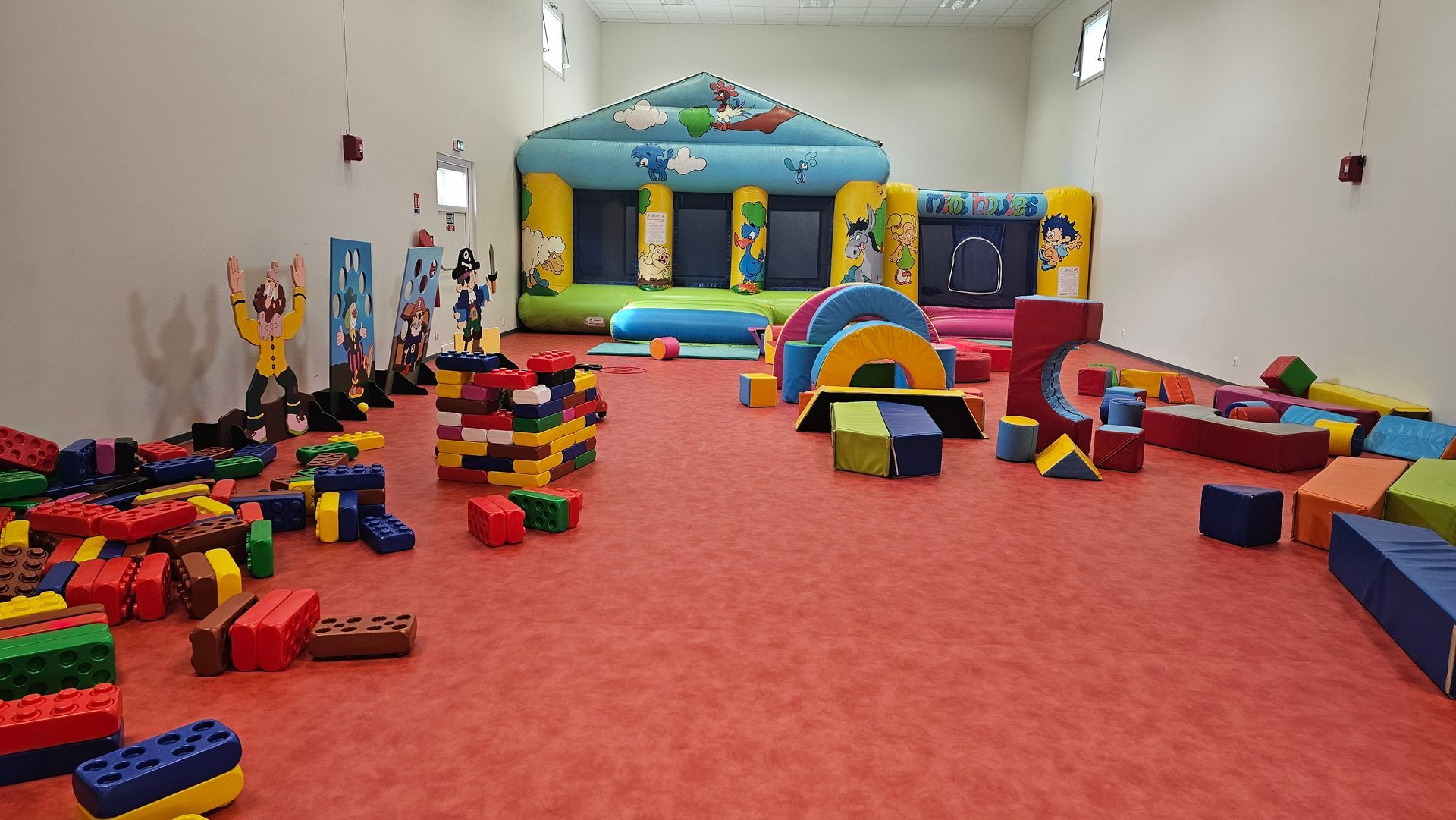 Aire de jeux intérieur avec structure gonflable et parcours.