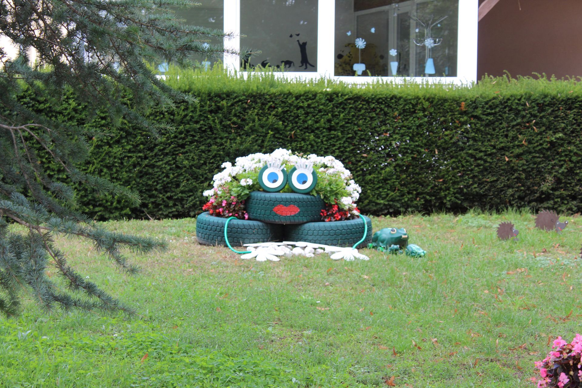 Une jardinière en forme de grenouille, fabriquée à partir de pneus et contenant des fleurs.