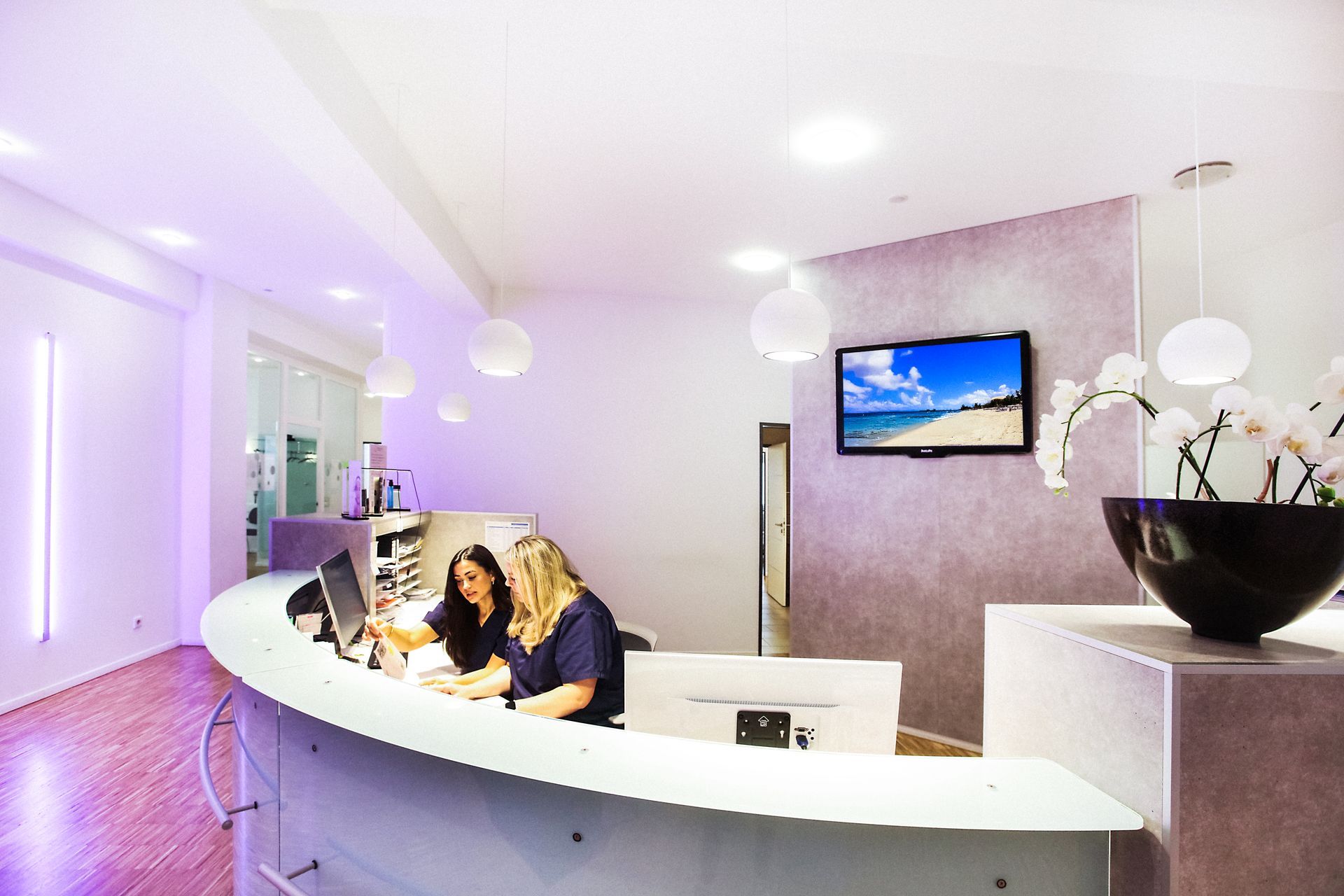 Ein Empfangstresen in einer Praxis mit einem Fernseher an der Wand. Dr. med. Claus-Peter Pack