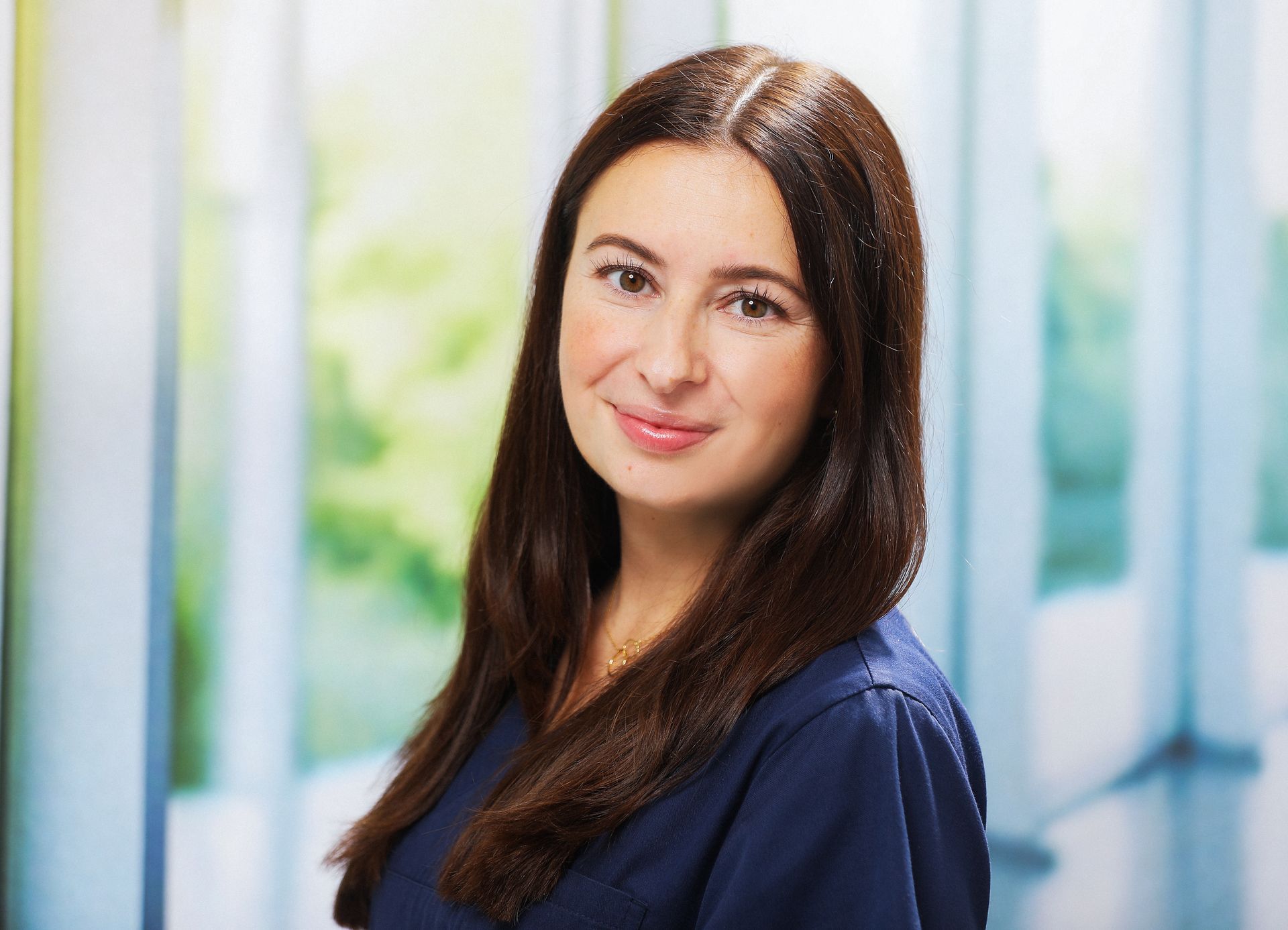 Eine Frau mit langen braunen Haaren lächelt in die Kamera.