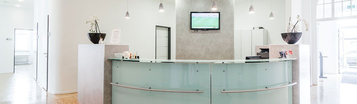 Ein Empfangstresen in einer Praxis mit einem Fernseher an der Wand. Dr. med. Claus-Peter Pack