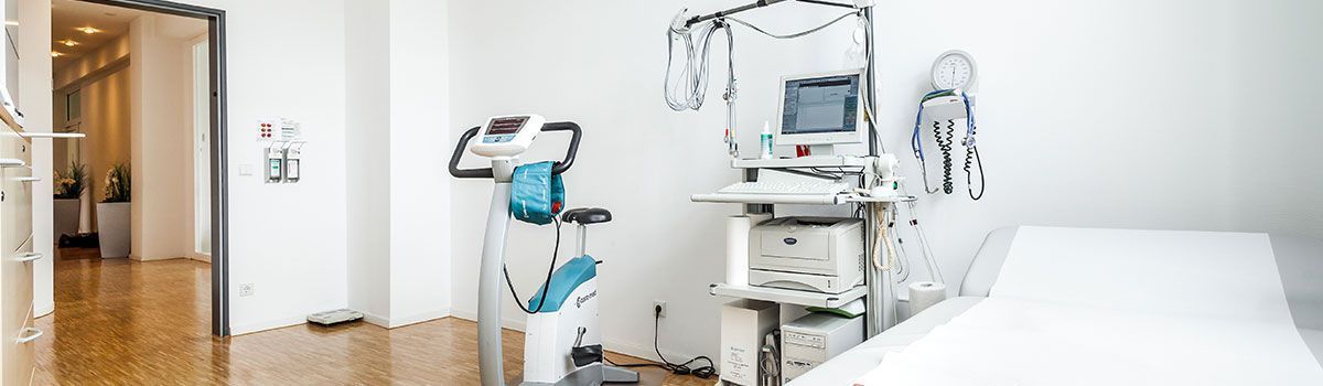 Eine Arztpraxis mit einem großen weißen Tisch und vielen medizinischen Geräten. Dr. med. Claus-Peter Pack