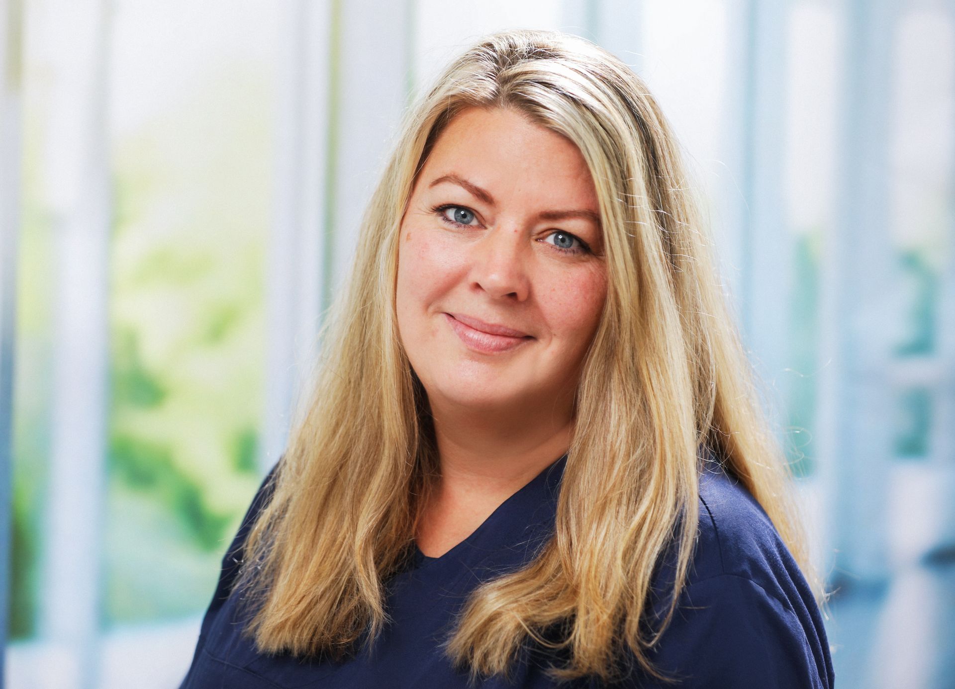 Eine Frau mit langen braunen Haaren und Perlenohrringen lächelt in die Kamera. Dr. med. Claus-Peter Pack