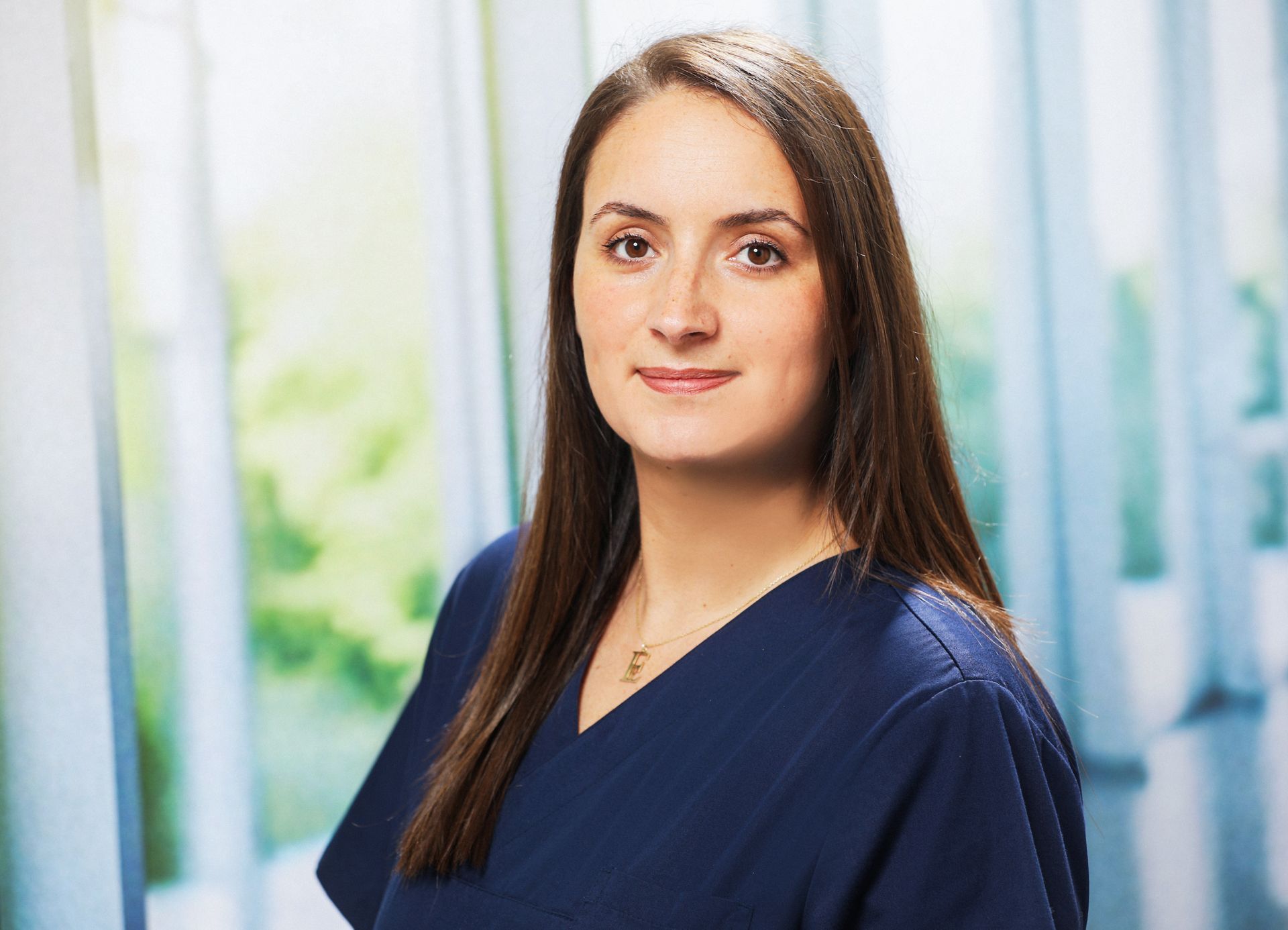 Eine Frau mit langen braunen Haaren und Perlenohrringen lächelt in die Kamera. Dr. med. Claus-Peter Pack