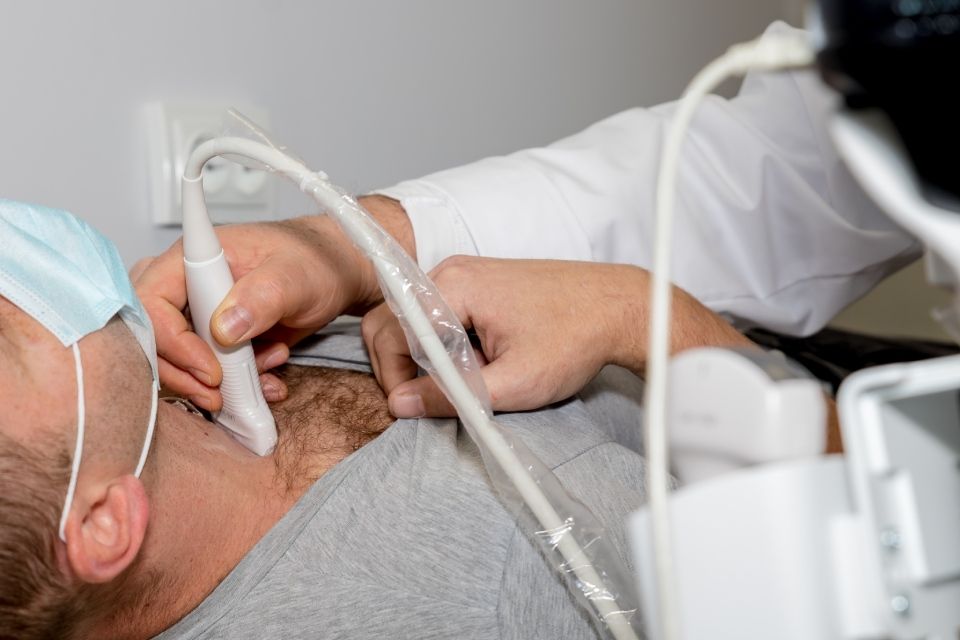 Ein Mann lässt von einem Arzt eine Ultraschalluntersuchung seines Halses durchführen.