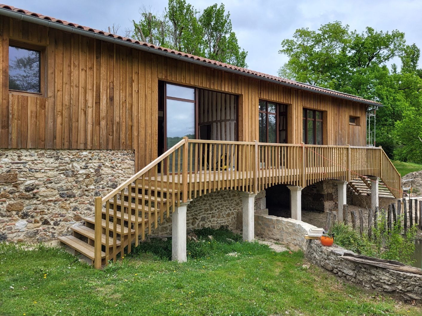 Photo de l'extérieur d'une maison possédant un bardage et une terrasse en bois.