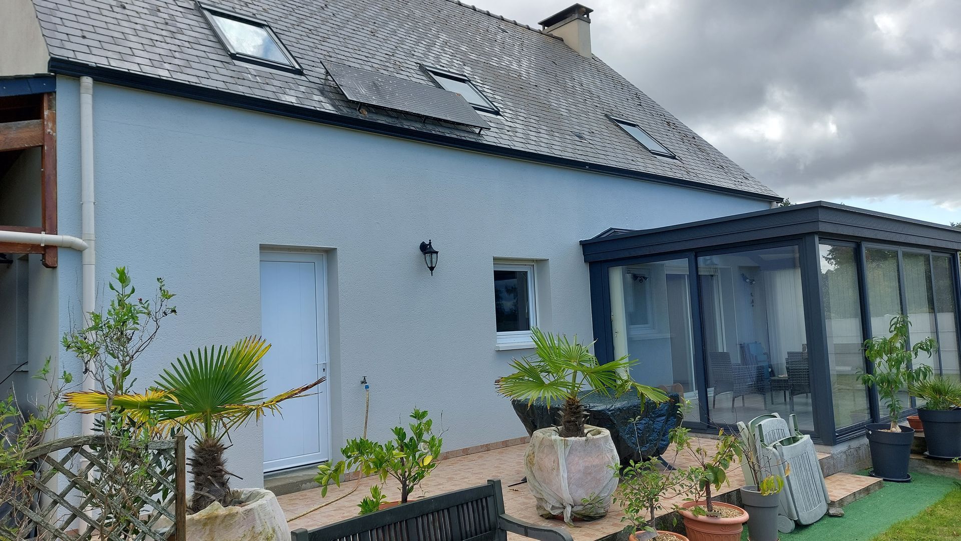 Un pavillon avec une façade blanche et une toiture en ardoises