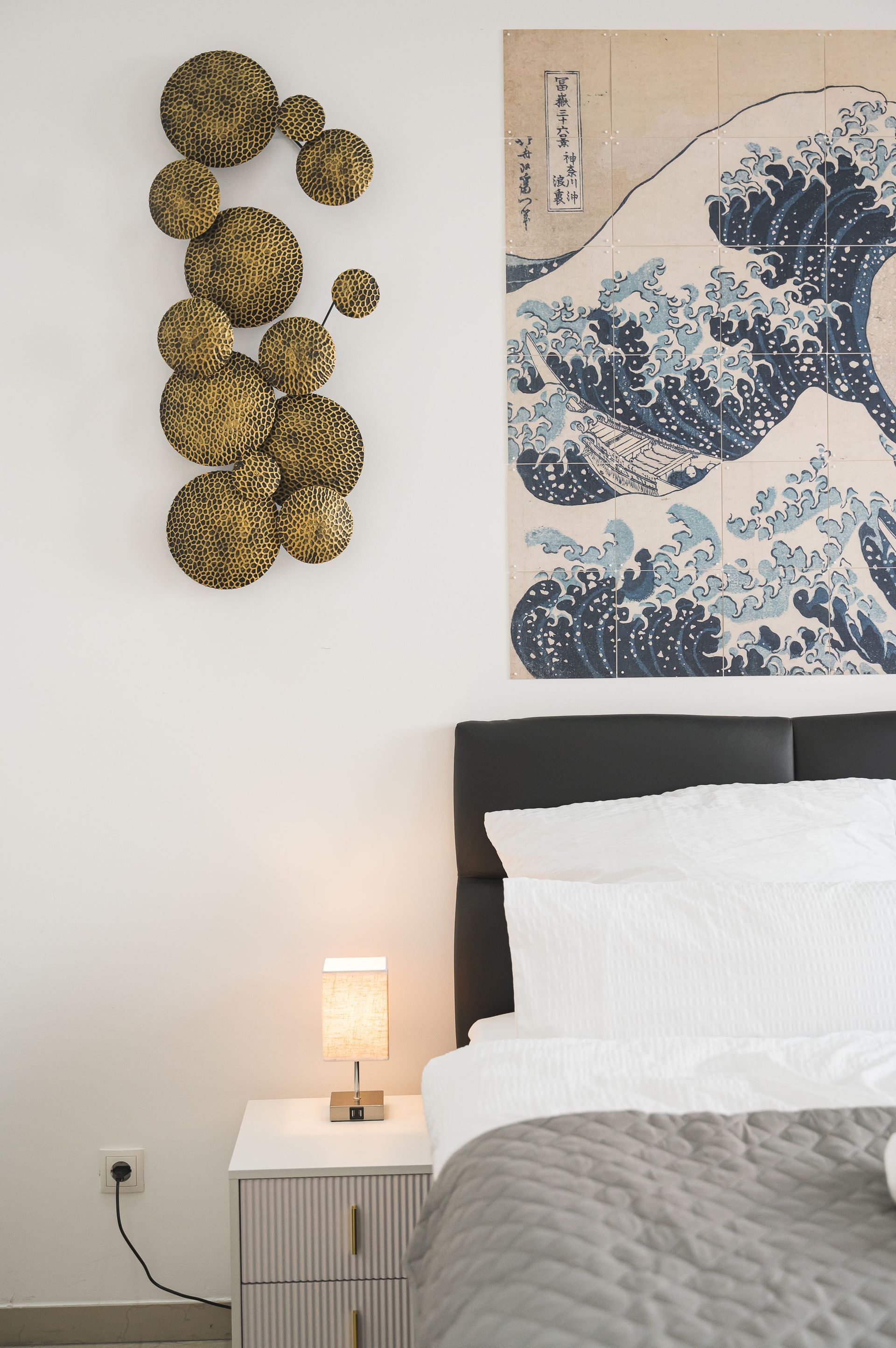 Bedroom with a bed, nightstand, art, and decorative gold circles on a white wall.