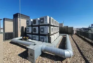 Un montón de aparatos de aire acondicionado están apilados uno encima del otro en el techo de un edificio.