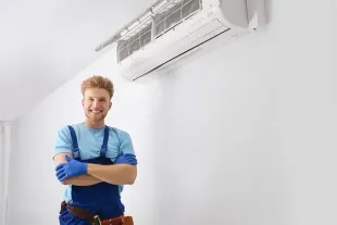 Un hombre está parado frente a un acondicionador de aire montado en la pared.