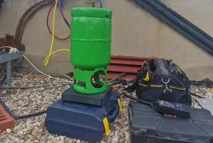 Un cilindro verde está encima de un contenedor azul.