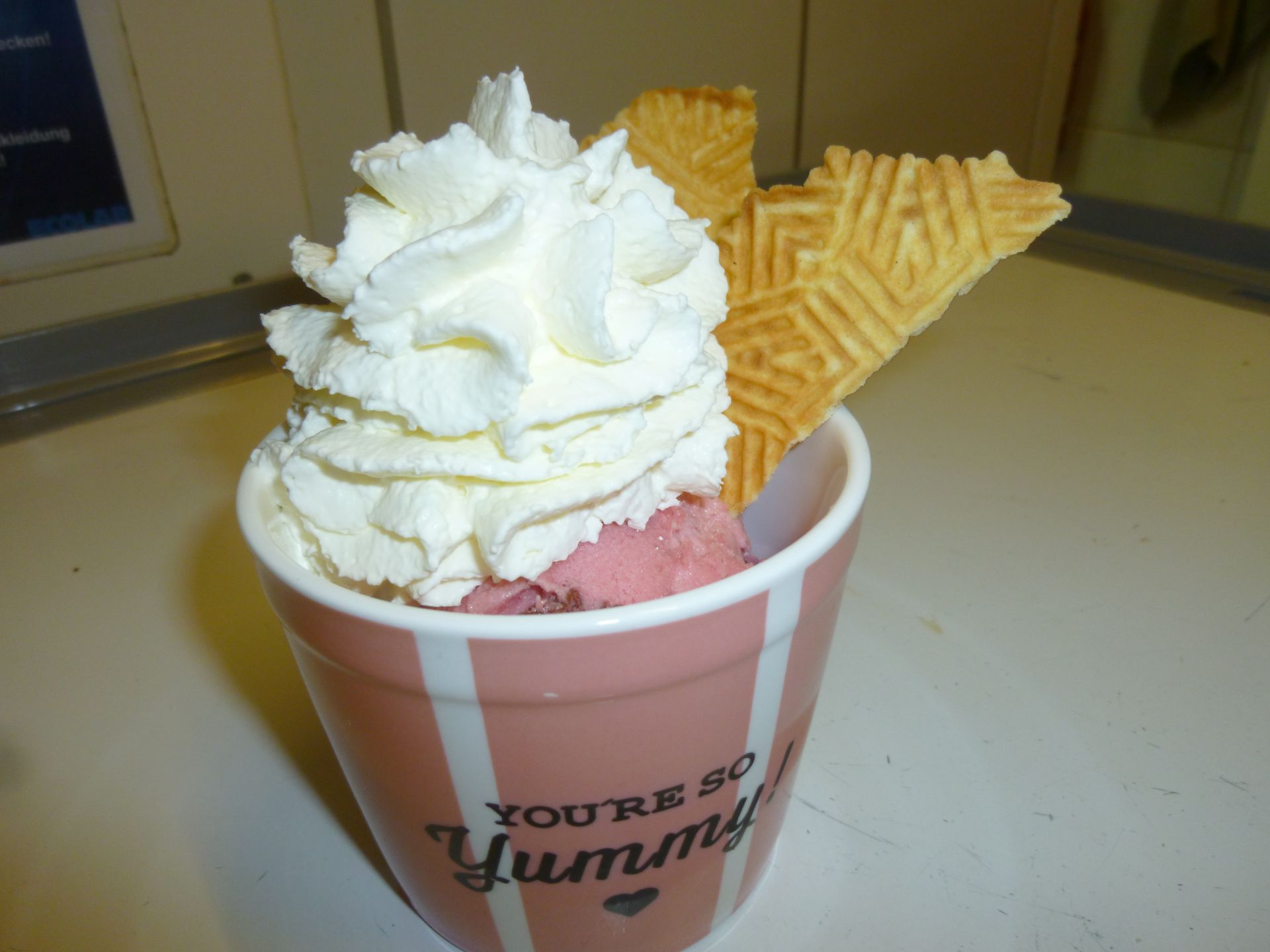 Eine Tasse Eis mit Schlagsahne und eine Waffeltüte sagt, du bist so lecker